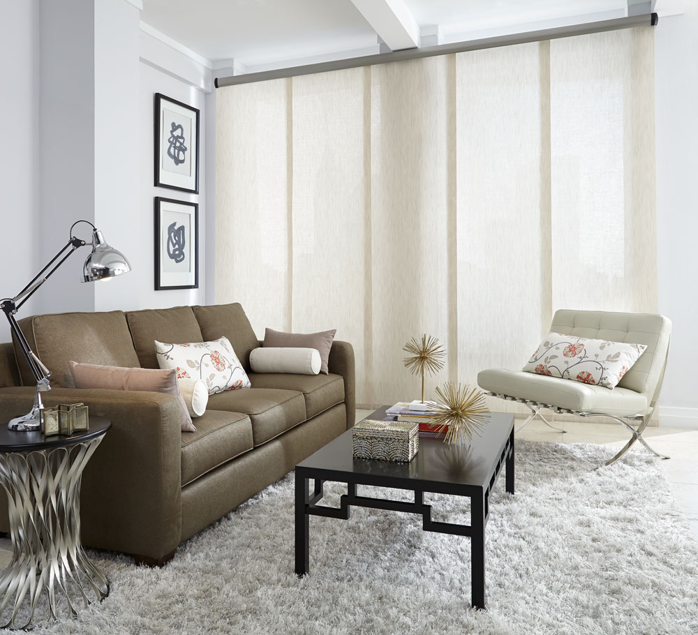White Genesis® panel track in the closed position in a picture window and a brown couch with custom Interior Masterpieces® pillows