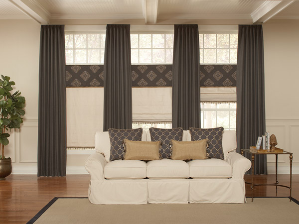 Interior Masterpieces® Draperies, Fabric Shades, Fabric Wrapped Cornices, and Custom Pillows Dark brown Interior Masterpieces® Draperies with tan Fabric Shades, dark brown geometric patterned Fabric Wrapped Cornices, and matching Custom Pillows on a cream colored couch