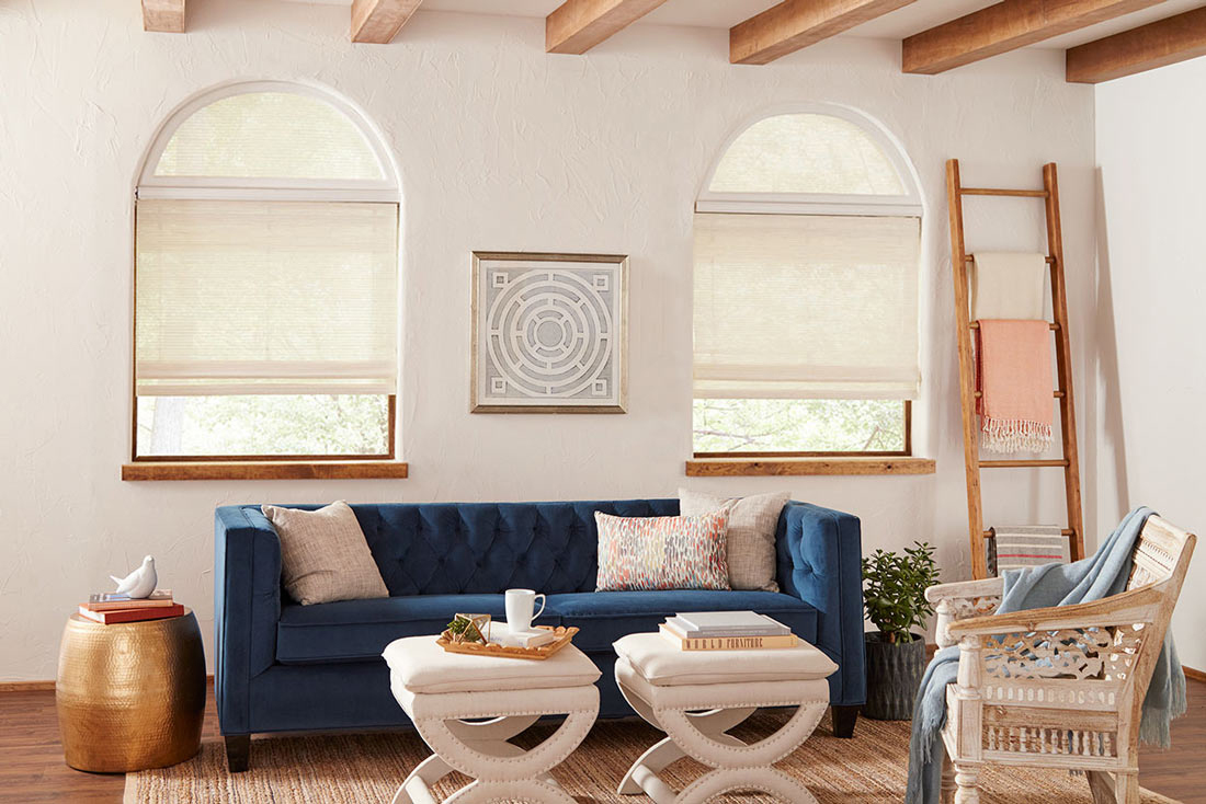 Manh Truc® Woven Wood Shades with Custom Shapes, Palladian Shelf & Interior Masterpieces® Custom Pillows two white Manh Truc® Woven Wood Shades with half circle Custom Shapes on top & Palladian Shelf in between behing a blue couch with custom pillows